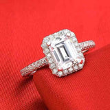 Silver engagement ring with a round blue sapphire center stone and prong setting on a red fabric background