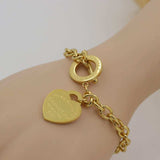 Gold charm heart bangle bracelet with toggle clasp on wrist, women's fine jewelry accessory