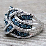 Silver women's cocktail ring with dark blue gemstones in prong setting on wooden surface