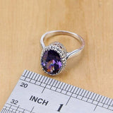 Silver ring with round purple amethyst gemstone on wooden surface with ruler showing size