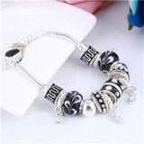 Silver charm bracelet with black and white patterned beads and dangling charms on a link chain