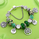 Silver Tree of Life charm bracelet with green and floral beads on green background