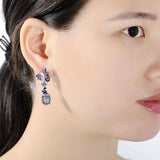 Luxury flower amethyst drop earrings in sterling silver worn by woman, trendy purple gemstone jewelry for women.