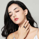 Woman wearing natural blue topaz ring in 14K rose gold with round stone and tension mount design
