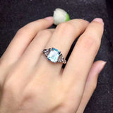 Natural blue aquamarine ring with oval gemstone set in sterling silver wedding band on woman's hand
