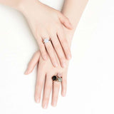 Hands wearing rose gold rings with round natural blue topaz gemstones in a classic wedding band style