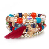 Vintage wristband beaded bracelet for women with colorful beads, silver charms, and a red feather accent in bohemian style