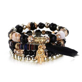 Vintage wristband beaded bracelet for women with black and gold beads, silver accents, charm and black feather tassel.